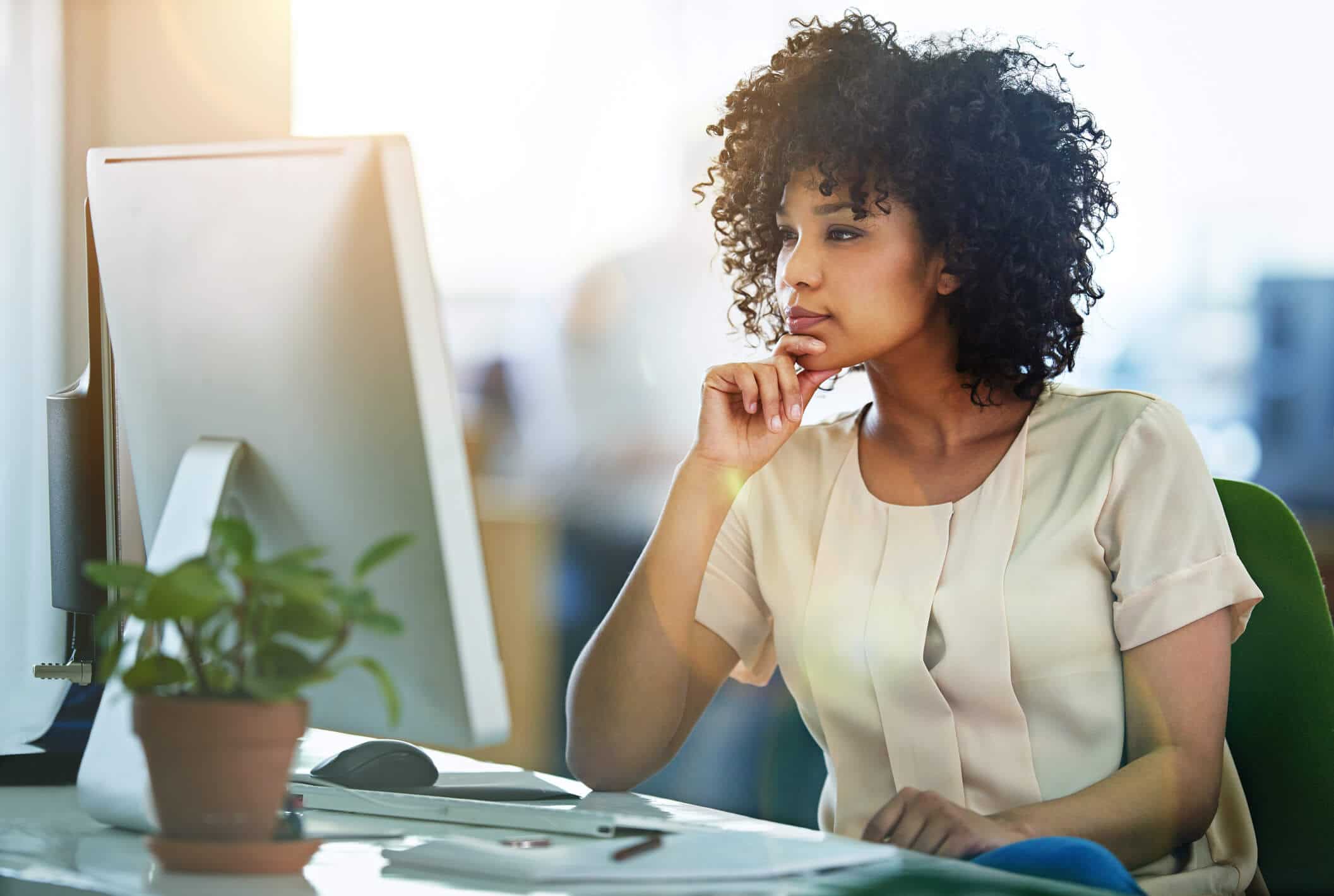 young businesswoman sitting at desk while looking at customer data on monitor